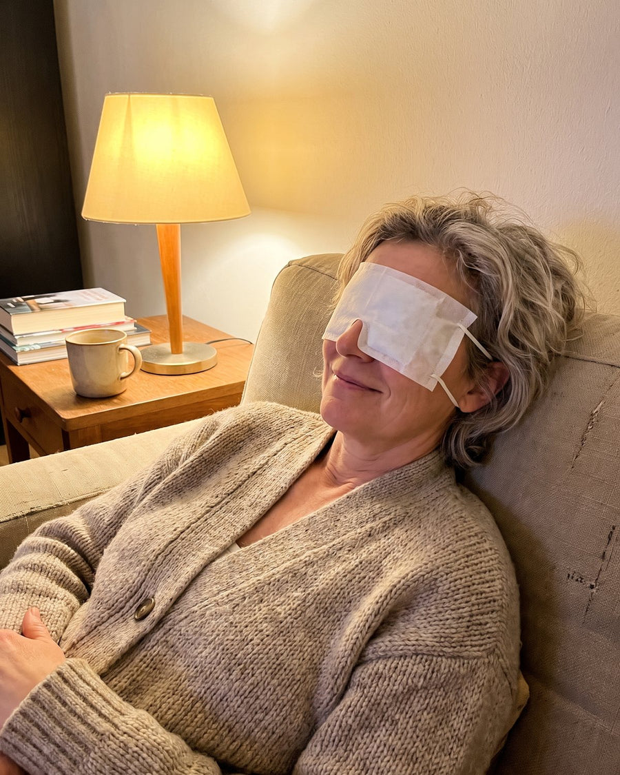 Frau entspannt mit Wärmemaske auf dem Sofa (Modell)